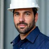 Foto professionale di Luca Conti, direttore lavori e gestione cantiere di Arte Casa Ristrutturazioni, con casco di sicurezza in un cantiere moderno.
